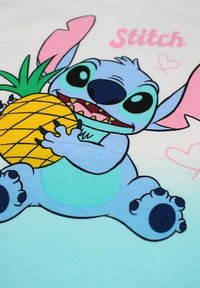 T-shirt en coton avec un personnage de dessin animé bleu aux grands yeux et aux accents roses, tenant un ananas jaune sur un fond clair.