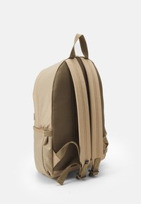 Zaino beige con esterno in nylon liscio e schienale in rete imbottito. Dotato di spallacci regolabili e tasche laterali. Design minimalista senza motivi.