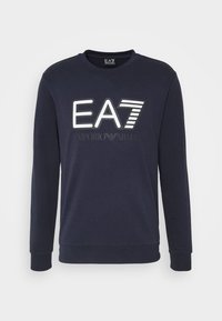 Granatowa bluza z długimi rękawami, okrągłym dekoltem i dużym białym logo "EA7" z paskami. Miękka, gładka tkanina, casualowy krój.