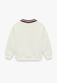 Kremowy sweatshirt z prążkowanym bordowym kołnierzem i mankietami. Charakteryzuje się luźnym krojem i miękką fakturą. Prosty design, widok z tyłu.