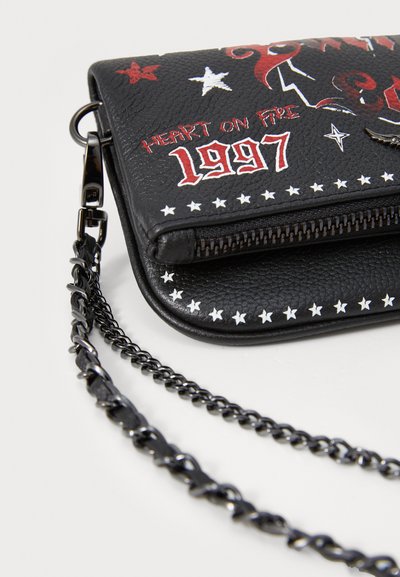Schwarze Kunstledertasche mit weißen Sternmustern und roten Grafiken, ausgestattet mit einem Reißverschluss und einem schwarzen Kettenriemen. Akzentuiert mit "Heart on Fire" und "1997."