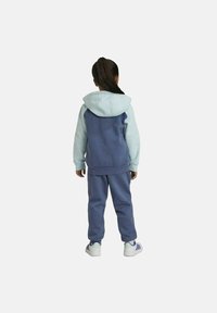 Conjunto atlético para niños que incluye una sudadera con capucha de color azul claro con la parte posterior azul más oscura, pantalones jogger a juego en azul y zapatillas blancas con detalles verdes.