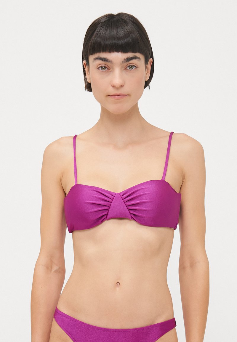 Fukšijas krāsas bikini tops ar plānām siksnām, ar savilkuma priekšpusi, lai piešķirtu tekstūru. Gluda materiāla, koordinējošs bikini apakšdaļa redzama.