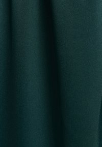 Tejido verde oscuro con una textura suave y mate, que presenta una ligera caída y sin patrones o hardware visibles.