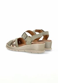 Sandalias beige con acentos metálicos, correas entrecruzadas y cierre de hebilla. Suela ligera con un ligero tacón en cuña. Tela texturizada.