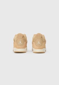 Svetlo rjave športne superge iz semiša z gladko teksturo, ki imajo bel logo Jumpman in kremasto barvo podplata. Zadašnji pogled prikazuje oblazinjen ovratnik in detajle.