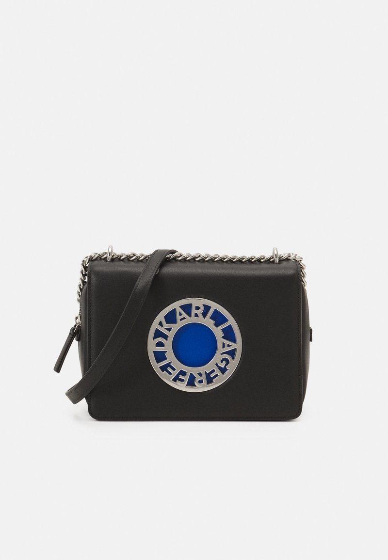 Sac à main rectangulaire en cuir noir avec bandoulière en chaîne argentée et plaque logo circulaire argentée et bleue portant l'inscription "Karl Lagerfeld" à l'avant.