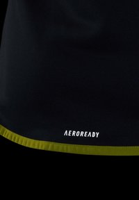 Maglietta sportiva nera con orlo verde; presenta il logo "AEROREADY" in bianco, tessuto liscio, design aderente, adatta per l'abbigliamento sportivo.