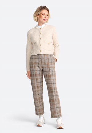 Light beige wool blend cardigan with rounded neck, two front pockets, and gold buttons, paired with brown plaid high-waisted trousers and sneakers.