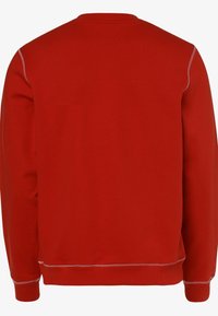 Sudadera roja con cuello redondo clásico, manga larga y detalles de costura en contraste. La tela parece suave con un dobladillo y puños de canalé.