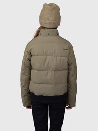 Pessoa vestindo um casaco puffer verde oliva e um gorro de malha bege, vista de costas contra um fundo plain.