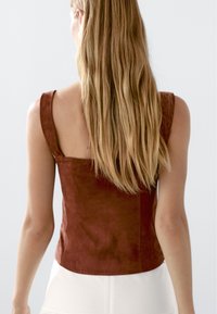 Bruine mouwloze top met een vierkante halslijn, gemaakt van zacht suède-achtig materiaal, met een getailleerd ontwerp en stikdetails langs de naden.