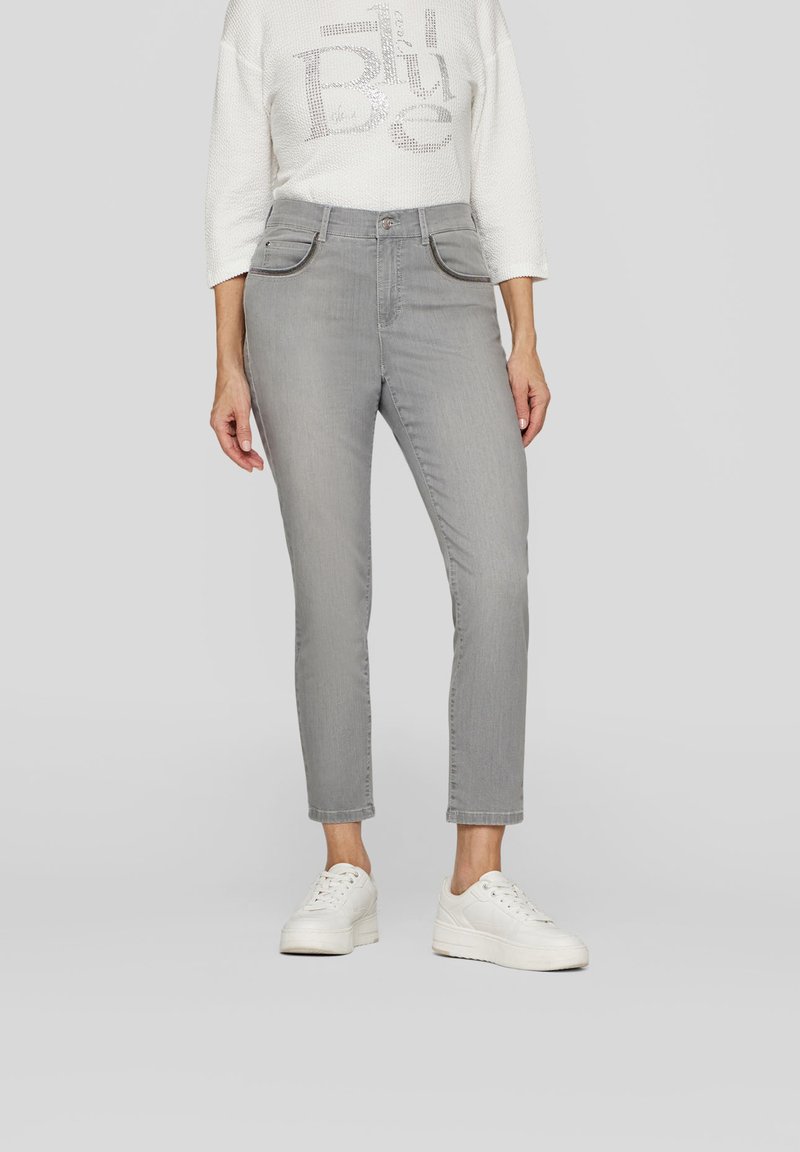 Gray jeans with a slim fit, featuring four pockets and a zip fly. Worn with a white textured top and white sneakers.