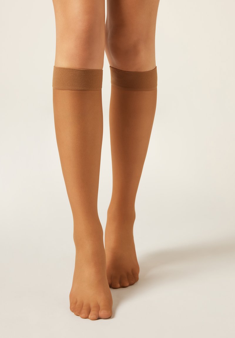 Poloprůhledné punčochy do výšky kolen v přírodní barvě s hladkou texturou a elastickými horními pásky ve stejné odstínu, navržené pro pohodlí a nositelnost.