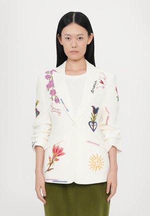 White blazer with colorful floral and heart embroidery. Features a notched lapel, patch pockets, and relaxed sleeves; paired with green skirt.