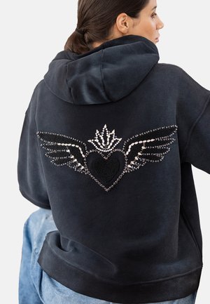 Black hoodie featuring a jeweled design on the back, with wings and a heart accent, made from soft fabric with a relaxed fit.