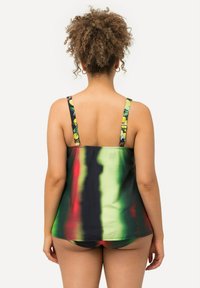 Tankini-topp med flerfärgad tie-dye-mönster, som har gröna, svarta och röda nyanser. Remmarna har fruktiga accenter. Mjukt, elastiskt tyg.