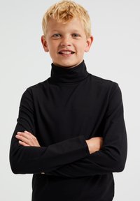 Fekete, hosszú ujjú garbó, sima anyagból készült, testhez simuló fazonú, varrat nélküli vállakkal, vidám gyermek viselésében.