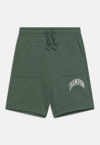 Pantalones cortos de algodón verde con cintura elástica y cordón. Cuenta con dos bolsillos frontales y el logo "CHAMPION" en blanco en la pierna izquierda.