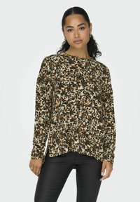 Langærmet top i et beige, brunt og grønt blomstermønster, lavet af blødt stof. Rundt afslutning og tætsiddende manchetter. Sammen med sorte bukser.