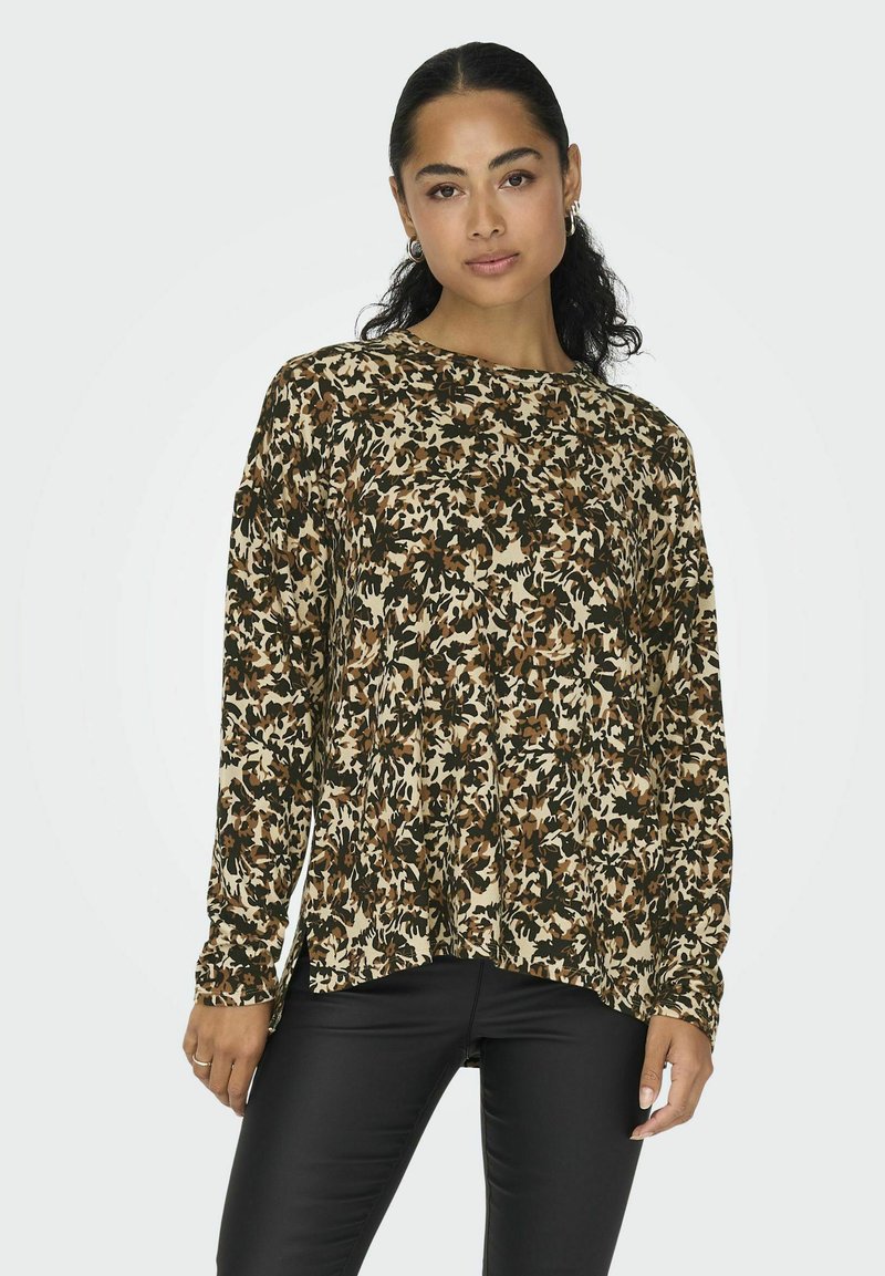 Langærmet top i et beige, brunt og grønt blomstermønster, lavet af blødt stof. Rundt afslutning og tætsiddende manchetter. Sammen med sorte bukser.