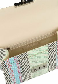 Bolso de mano tejido con un exterior de patrón que presenta acentos en verde, azul y rojo. El interior es beige con un bolsillo con cremallera y múltiples compartimentos.