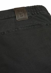 Zwarte textured broek met elastische tailleband, met een bruin leren label met "M5" erop geperst en een enkele achterzak.