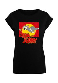 Mustat t-paidat, joissa on värikäs "Tom ja Jerry" -kuvio punaisella taustalla, esittäen Tomia ajamassa Jerryä takaa, rohkealla keltaisella tekstillä.