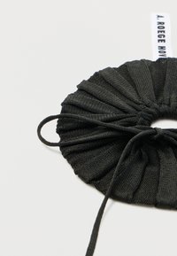 Scrunchie in tessuto nero con texture plissettata e un sottile anello per una chiusura sicura. Presenta un'etichetta con il logo "A. ROEGE HOVE."