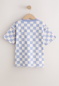 T-shirt met korte mouwen met een blauw-wit geruit patroon, hangend aan een houten hanger tegen een effen muur.