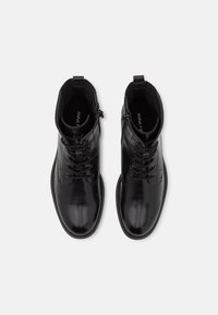 Botas de cuero negro hasta el tobillo con un acabado suave, cordones en la parte delantera y cremallera lateral. Acentos texturizados en el cuello y detalles de costura.