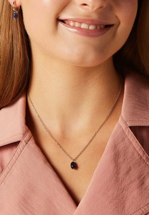 Zilveren ketting met ovale marineblauwe edelsteenhanger; bijpassende oorringen. Beide stukken hebben een slank design en een gepolijste afwerking.