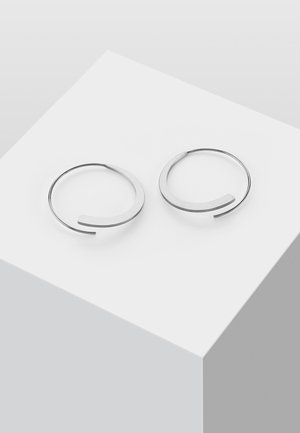 Silberne Creolen mit minimalistischem Design, das eine gebogene Form und ein offenes Ende aufweist, wobei eine glatte metallische Textur betont wird.