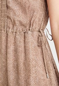 Ruskea mekko, jossa on matelijakuosiset tekstuurit, kerätty vyötärö ja säädettävä nyöri. Sileä kangas, jossa on hieno kiilto ja hopeiset yksityiskohdat.