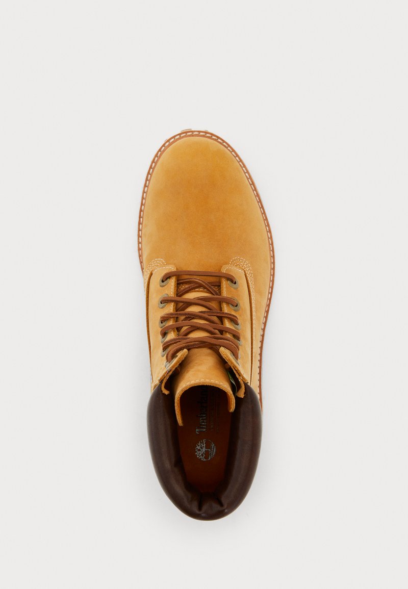 Stivali stringati in pelle tan con colletto imbottito marrone scuro, cuciture visibili e logo Timberland all'interno della soletta, visti dall'alto su sfondo bianco.