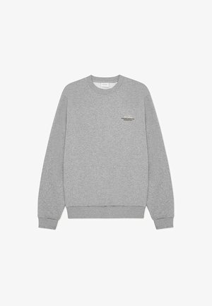 Siva jopa iz bombažne mešanice z okroglim izrezom in rebrastimi manšetami. Na prsih je tiskan logotip. Preprost, klasičen dizajn.