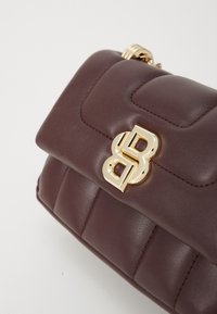 Bolso de cuero acolchado marrón oscuro con un cierre de logo de doble B dorado y forma rectangular redondeada sobre un fondo blanco.