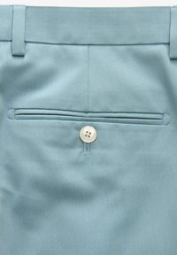 Lichtblauwe broek met een gladde textuur, voorzien van een achterzak die is afgesloten met een ronde, viergaatjesknop en gestructureerde naaddetails.