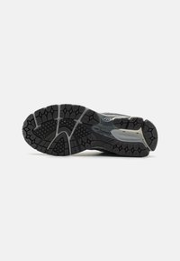 Semelle de chaussure de sport noire en caoutchouc texturé pour une meilleure adhérence, avec un motif hexagonal et des bords renforcés pour la durabilité et le soutien.