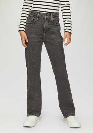 Zwarte denim flared jeans met een hoge taille, vijf zakken, riemlussen en contrasterende stiksels, gecombineerd met witte sneakers.