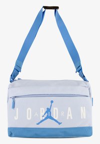Ανοιχτό μπλε τσάντα ώμου με ρυθμιζόμενο λουρί, τσέπη με φερμουάρ και λευκό κείμενο "JORDAN". Διαθέτει μπλε λογότυπο μπάσκετ και υφή.