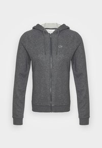 Grå zip-up hoodie gjord av mjukt tyg, med en dragsko på huvan, ribbade ärmslut och en liten logotyp på bröstet.