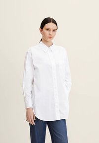 White long-sleeve button-up shirt made of smooth fabric with a collar, featuring a relaxed fit and a single breast pocket.