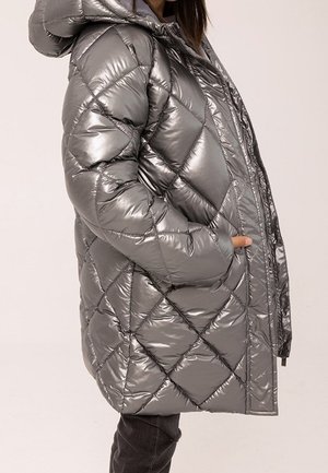 Doudoune argentée avec capuche, présentant un design matelassé et une finition brillante. Comprend des poches latérales et une fermeture éclair frontale complète.