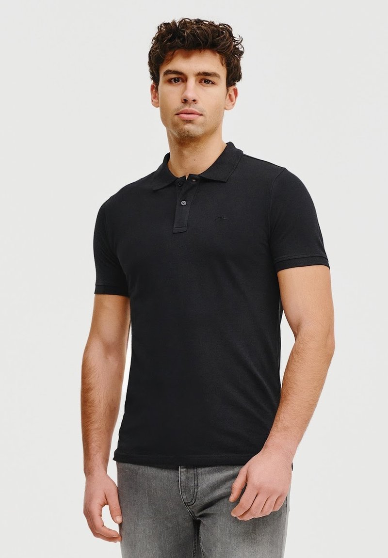 Czarna koszulka polo z bawełny, z dwoma guzikami i krótkimi rękawami. W połączeniu z szarymi dżinsami, prezentuje dopasowany krój.