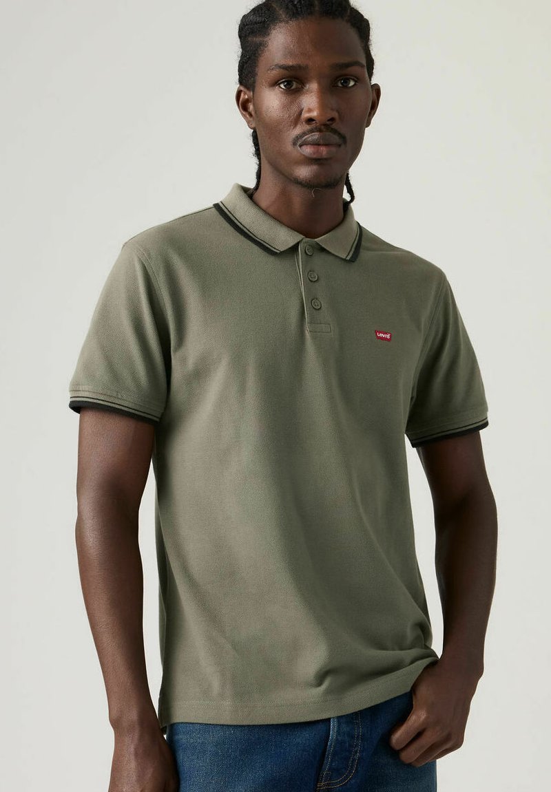Polo verde realizzata in cotone, con colletto, tre bottoni e dettagli neri a contrasto sulle maniche e sul colletto. Piccolo logo sul petto.