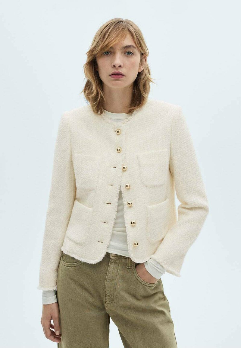 White textured bl blazer with gold buttons, featuring four front pockets and a cropped hem, worn over a long-sleeve white shirt.