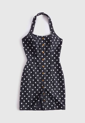 Robe noire à col halter avec pois blancs, fermeture à boutons sur le devant et silhouette ajustée, posée à plat sur un fond blanc.
