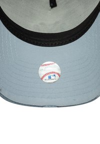 Cappellino da baseball in tessuto grigio chiaro con visiera nera; presenta un adesivo rotondo del logo MLB sul lato inferiore. Design con visiera piatta, superficie testurizzata.