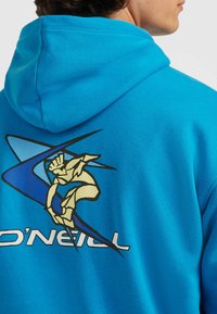 Sweat à capuche bleu avec un imprimé graphique d'un surfeur en accents jaunes et bleus au dos ; comporte une capuche à cordon de serrage et une texture douce.